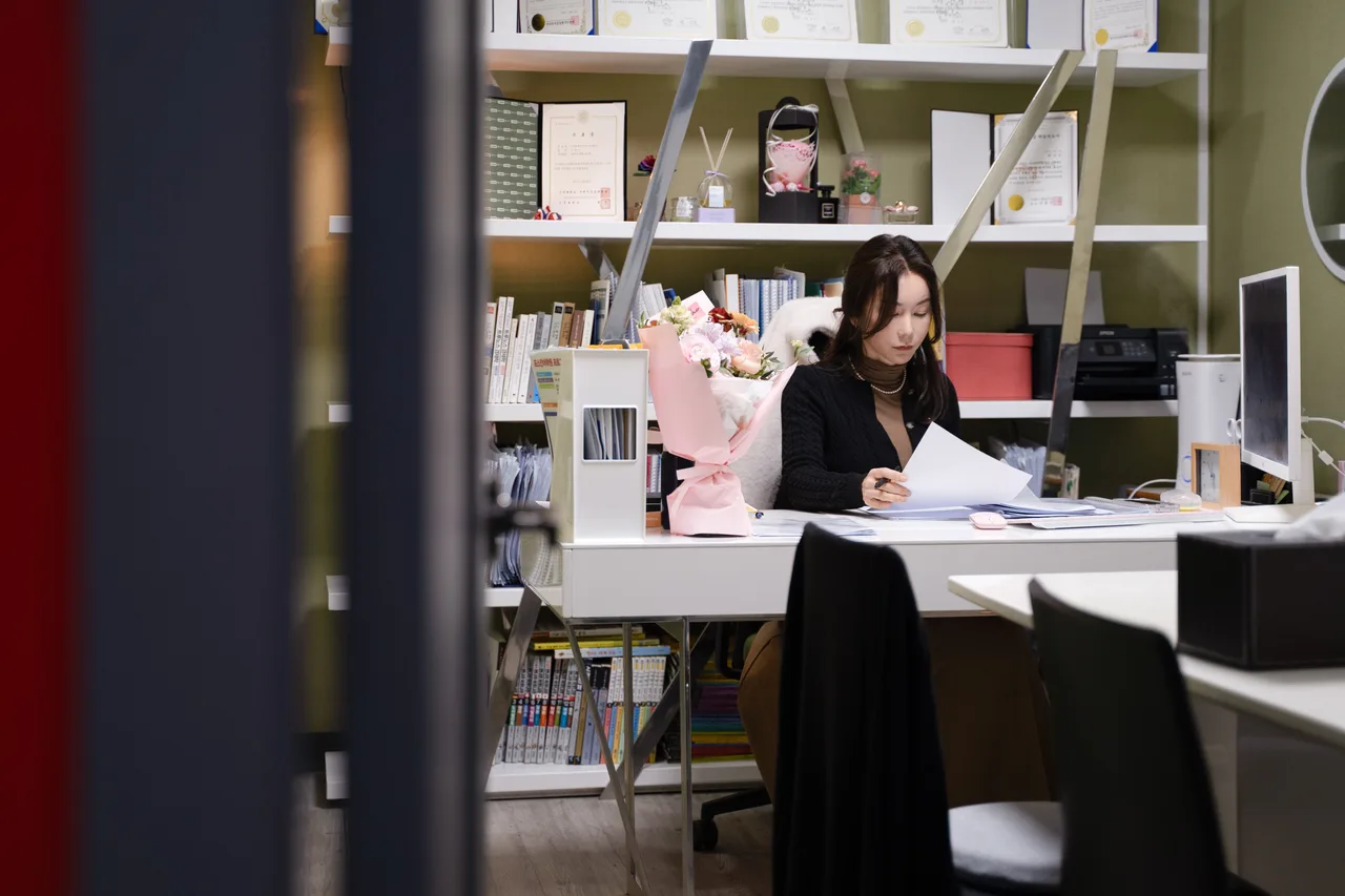 박선미 원장이 자격증과 교육 서적이 놓인 책장을 배경으로 책상에서 검사 결과지를 살펴보고 있다.